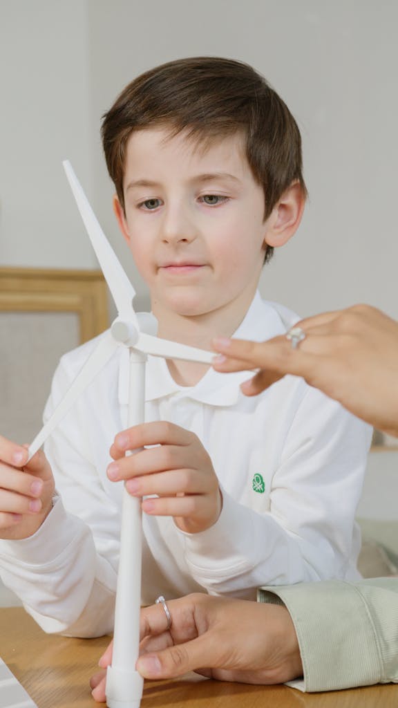 A young boy engaged in learning with a wind turbine model indoors.